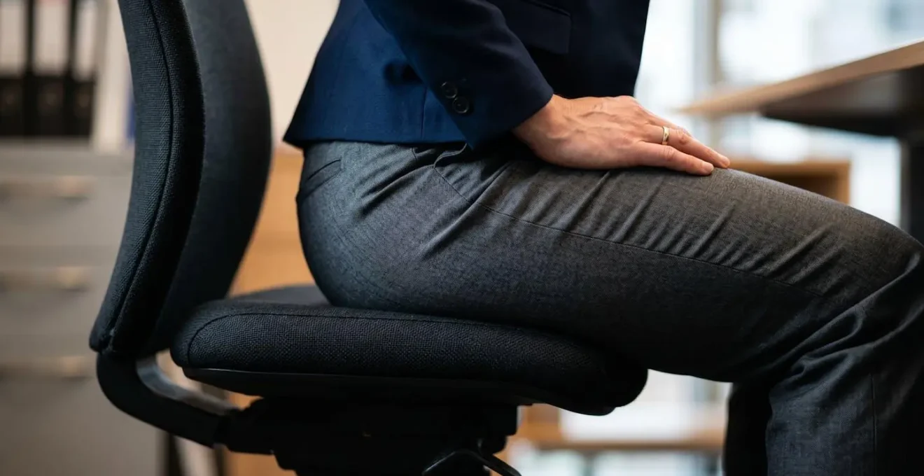 Office worker demonstrating subtle glute activation exercise while seated at desk